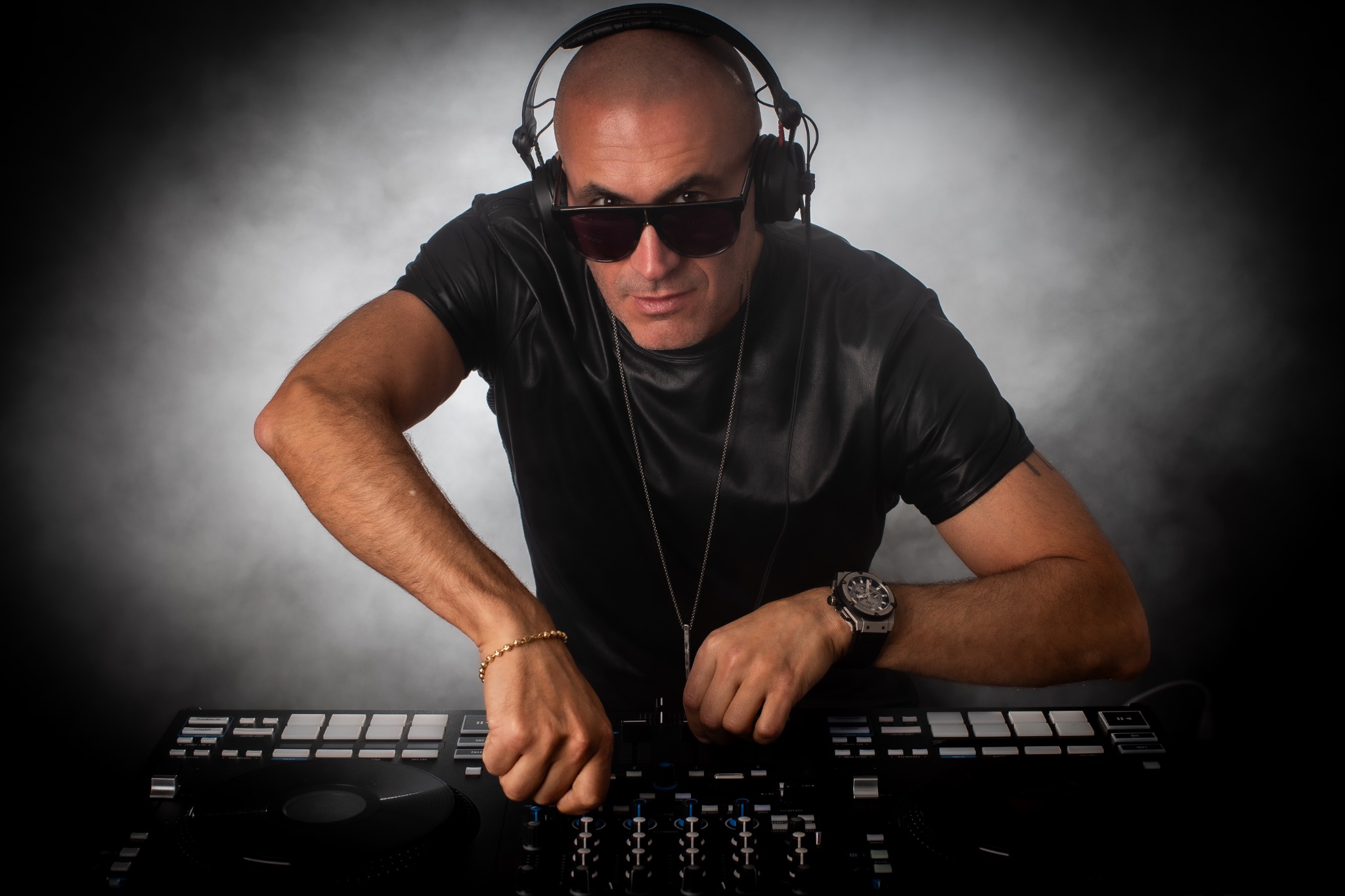 Alichenzo wearing headphones and sunglasses at the DJ decks